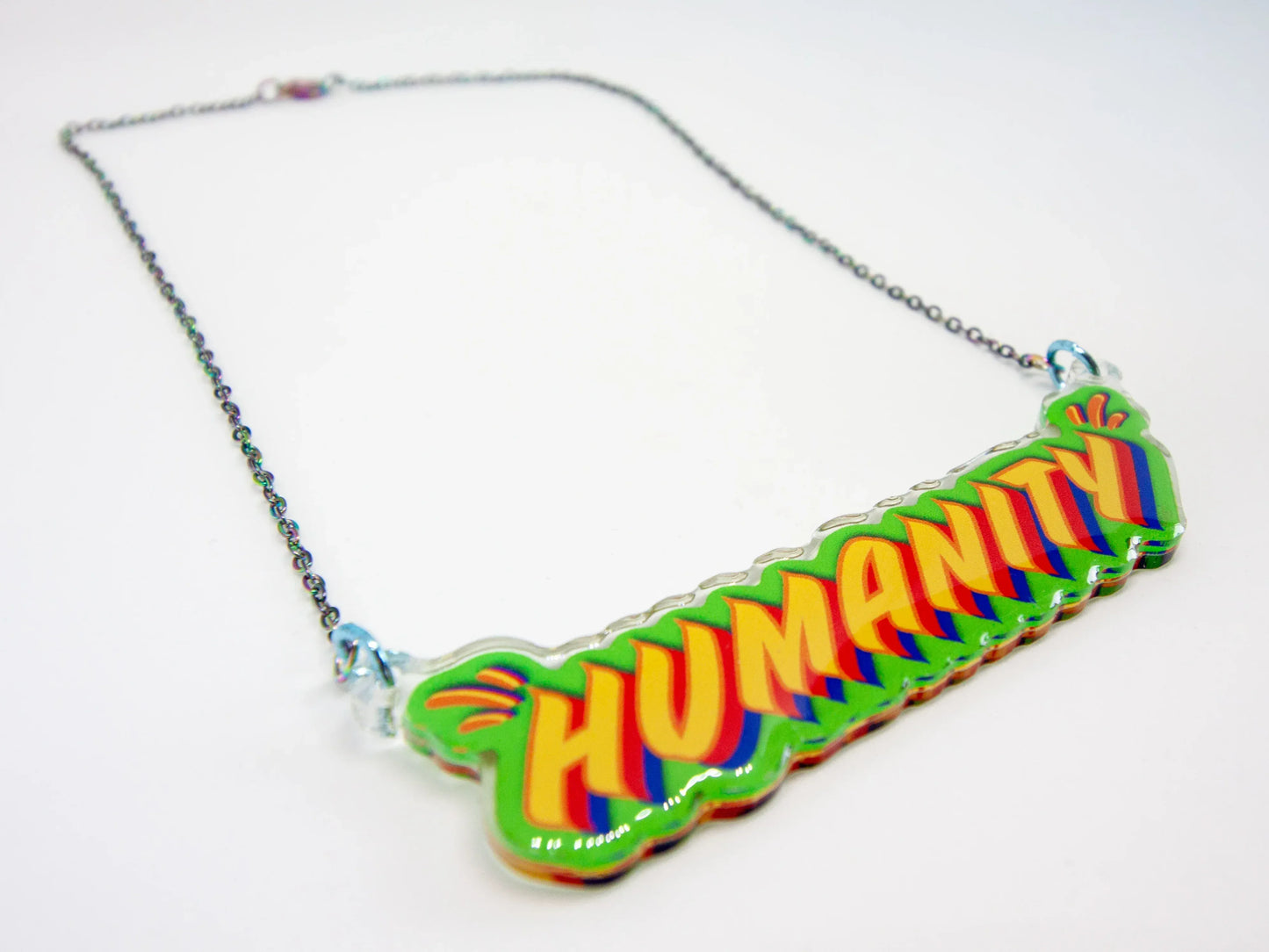 Necklace with a colourful 'HUMANITY' pendant on a white background - design and co-right by Stoofy.