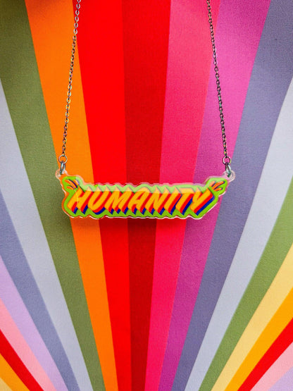'HUMANITY' necklace on a colourful striped background - a jewellery piece from Stoofy’s Primary Comcerns Original Art Collection - designed by UK mixed media artist Stoofy. 