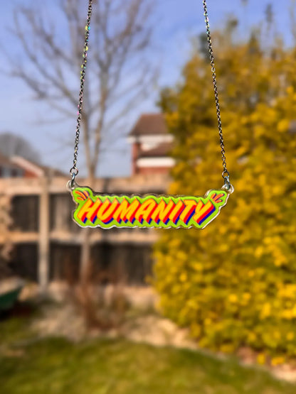 Stoofy’s 'Humanity' necklace with a blurred outdoor background. Copyright and design by Stoofy