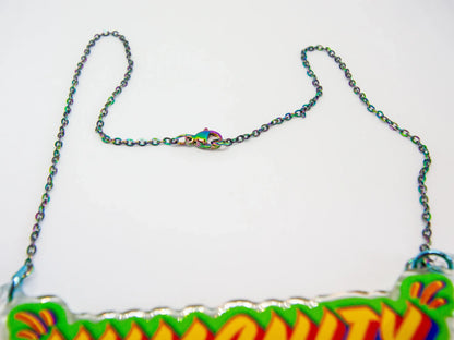 Close up of stainless steel oil slick chain and clasp with colourful 'HUMANITY' pendant on a white background by UK artist, Stoofy. 