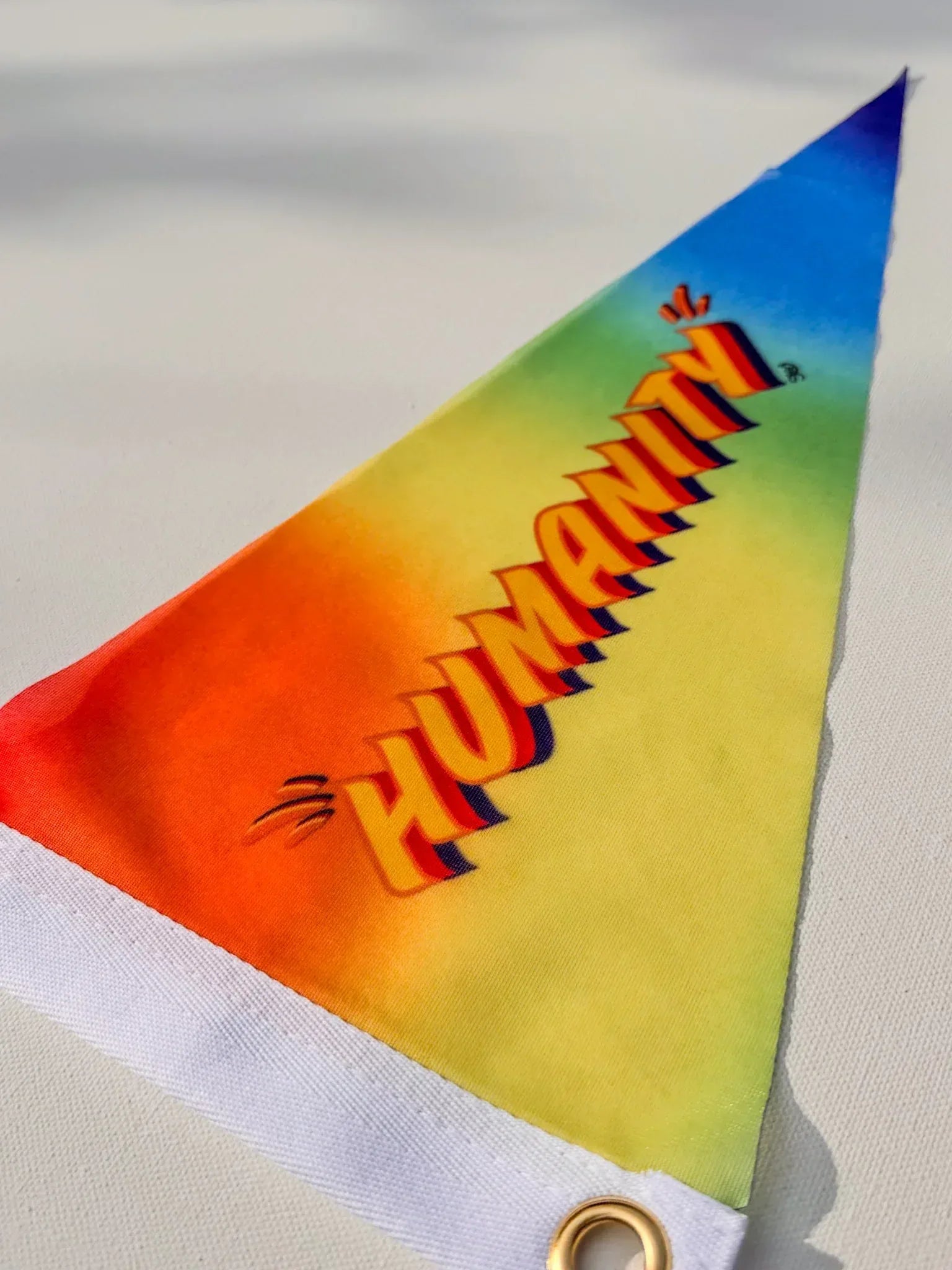 Triangular pennant flag with 'HUMANITY' printed on it against a light background. Design and copyright by Stoofy.
