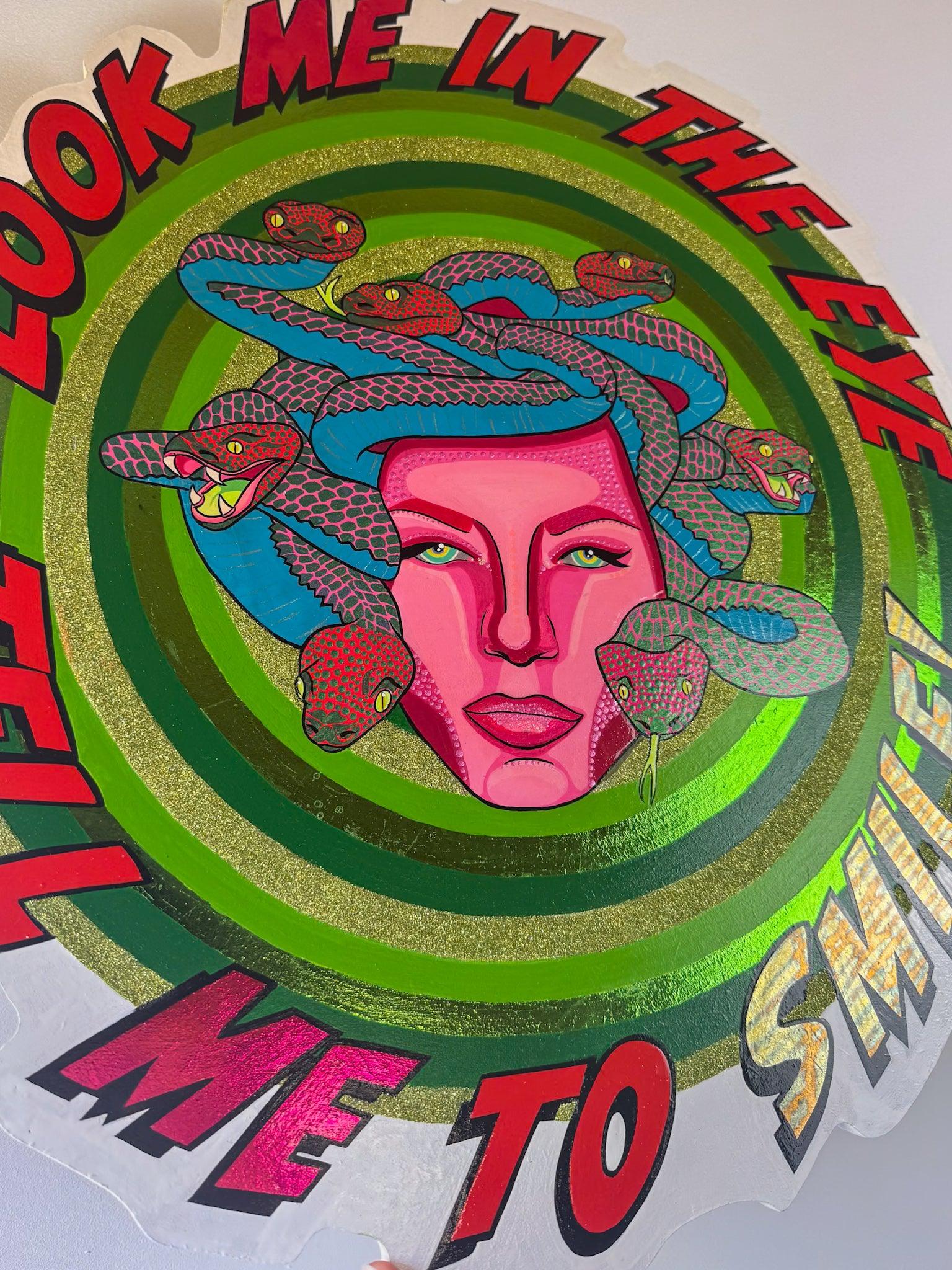 Close detail of Look Me in the Eye — Tell Me to Smile! by Stoofy, showing Medusa's face and the density of snake detail. The magenta pink face is covered in individually applied Ben-Day dots. Blue and red-pink snakes with scale-by-scale detailing surround her. Gold-green glitter on the concentric rings is visible at the edges. Mixed media original on hand-cut wood panel by Stoofy.