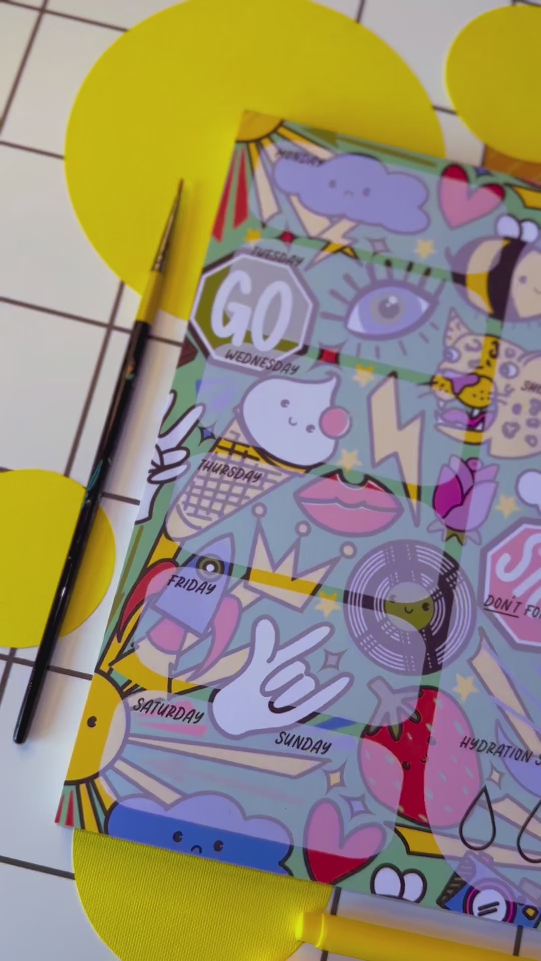 Video of a4 desk planner by the Stoofy store. Fun. Dopamine. Stationary lover. ADHD planner. Illustrated pattern including: suns, leopards, records, hearts, ice cream, crown, peace hand sign, lips, rocket, moon, strawberry, rose, cloud, four leaf clover, stop sign, go sign, eye, bumble bee, lightning, camera, chocolate. Close up details. Design and copyright owned by Stoofy.